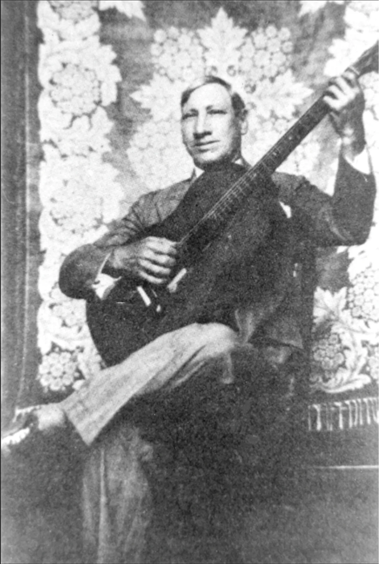 Alfredo Português sentado com um instrumento de cordas.